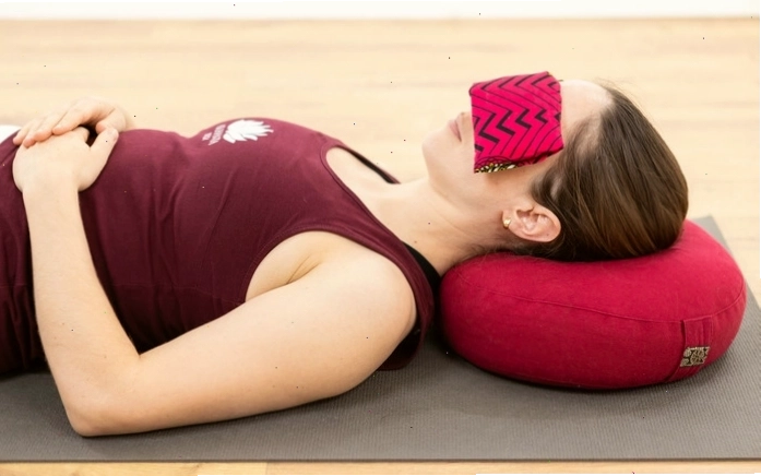 Người phụ nữ tập yoga tại nhà với các đạo cụ hỗ trợ